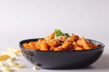 Creamy penne pasta in rich red sauce topped with grilled chicken, cheese, chili flakes and cilantro