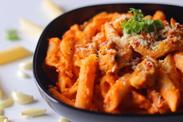 Creamy penne pasta in rich red sauce topped with grilled chicken, cheese, chili flakes and cilantro