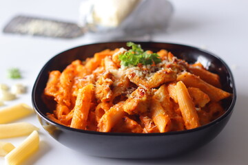 Creamy penne pasta in rich red sauce topped with grilled chicken, cheese, chili flakes and cilantro