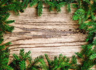 Christmas tree spruce branches with garland and bokeh on old wooden background with copy space. Design element.