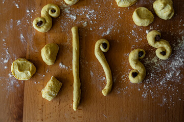 Process of making traditional Swedish saffron buns. Step by step of making S-shaped yeast buns spiced with saffron and decorated with raisins on wooden board.