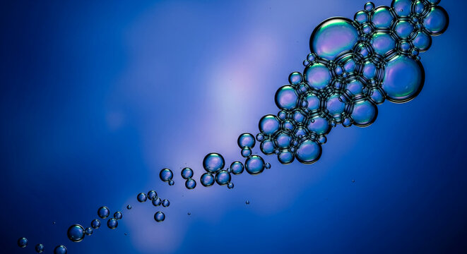 Cluster of iridescent bubbles against gradient blue backdrop, creating organic texture, representing fluidity, connection, and abstract visual for science concepts