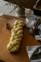 Unbaked challah bread sprinkled with sea salt flakes and cumin on wooden board.