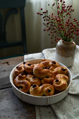 Homemade Swedish saffron buns on wooden table. Traditional treat eaten on Saint Lucia Day and during Advent. Spiced with saffron and decorated with raisins.