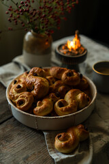 Homemade Swedish saffron buns and coffee on wooden table. Traditional treat eaten on Saint Lucia Day and during Advent. Spiced with saffron and decorated with raisins.