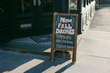 Sign outside a cafe featuring new fall drinks including pumpkin spice, matcha, and shaken espresso