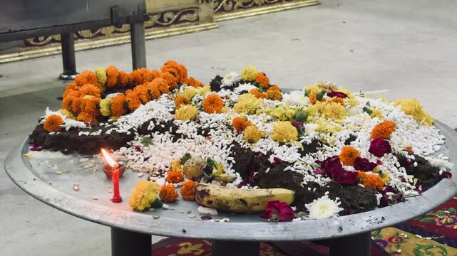temple prasad (offering) beautifully arranged with fresh marigold, rose, and jasmine flowers along with fruits and incense in a Hindu temple. The background shows the holy word "Sai"