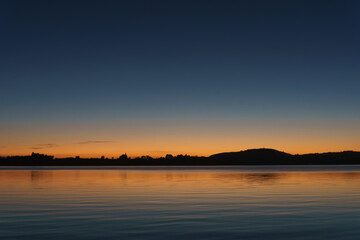 Blue of sky and water separated by orange and red of sunrise