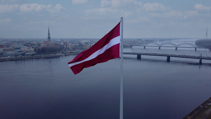 Drone View Of Riga Old Town With Latvian Flag Waving In Foreground Aerial Panorama Of Historic City Center, Daugava River And Urban Skyline On A Outumn Day In Latvia