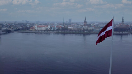 Drone View Of Riga Old Town With Latvian Flag Waving In Foreground Aerial Panorama Of Historic City Center, Daugava River And Urban Skyline On A Outumn Day In Latvia