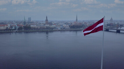 Drone View Of Riga Old Town With Latvian Flag Waving In Foreground Aerial Panorama Of Historic City Center, Daugava River And Urban Skyline On A Outumn Day In Latvia
