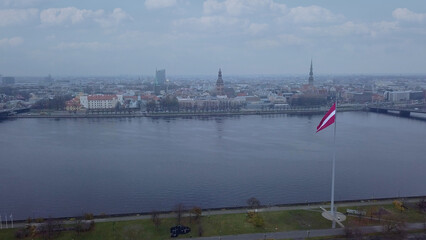 Drone View Of Riga Old Town With Latvian Flag Waving In Foreground Aerial Panorama Of Historic City Center, Daugava River And Urban Skyline On A Outumn Day In Latvia