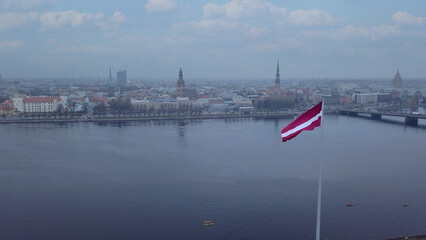 Drone View Of Riga Old Town With Latvian Flag Waving In Foreground Aerial Panorama Of Historic City Center, Daugava River And Urban Skyline On A Outumn Day In Latvia