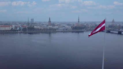 Drone View Of Riga Old Town With Latvian Flag Waving In Foreground Aerial Panorama Of Historic City Center, Daugava River And Urban Skyline On A Outumn Day In Latvia