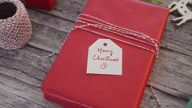 A woman preparing a Christmas present wrapped with red paper. 