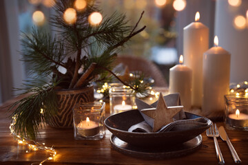 Elegant table decoration for a christmas dinner. Romantic dinner concept with burning candles in the evening at a restaurant. Close-up with golden bokeh lights. Background for seasonal an holiday gast