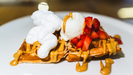 Crispy waffle topped with vanilla ice cream, chocolate sauce, caramel, and fresh fruits. A decadent dessert ready to eat, perfect for indulgent treats and cafes.
