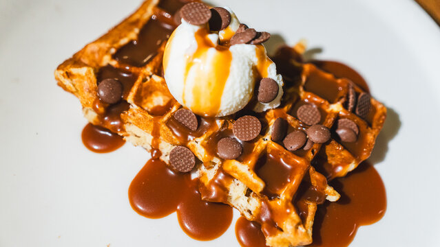 Crispy waffle topped with vanilla ice cream, chocolate sauce, caramel, and fresh fruits. A decadent dessert ready to eat, perfect for indulgent treats and cafes.