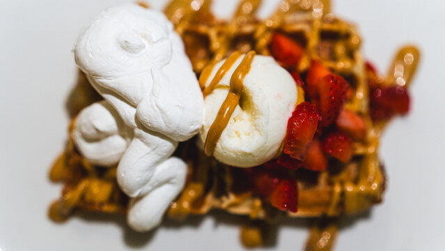 Crispy waffle topped with vanilla ice cream, chocolate sauce, caramel, and fresh fruits. A decadent dessert ready to eat, perfect for indulgent treats and cafes. - Powered by Adobe