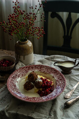 Traditional Swedish meatballs with mashed potatoes, cranberries and creamy gravy in vintage plate on wooden table. Homemade dinner. Comfort food.