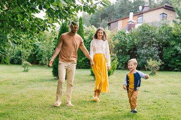 Fototapeta premium Expecting Parents Walking With Happy Son Outdoors
