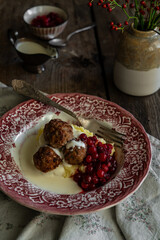 Traditional Swedish meatballs with mashed potatoes, cranberries and creamy gravy in vintage plate on wooden table. Homemade dinner. Comfort food.