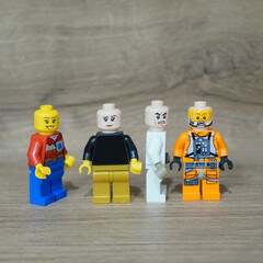 Naklejka premium Four Lego minifigures standing on a wooden surface, ready for adventure