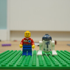 Naklejka premium Lego minifigure and R2-D2 droid standing on a green baseplate