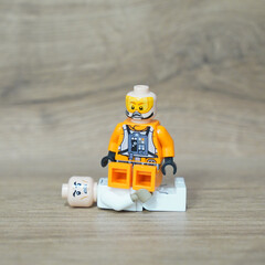 Naklejka premium Lego minifigure in orange pilot suit sitting on another Lego figure