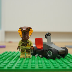 Naklejka premium Lego Ninjago character with a cobra head and a small race car on a green base