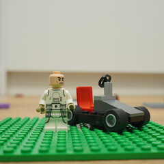 Naklejka premium Lego minifigure and race car on a green baseplate, creative toy concept