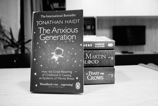 The Anxious Generation book by Jonathan Haidt, stacked with other books