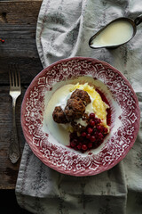 Traditional Swedish meatballs with mashed potatoes, cranberries and creamy gravy in vintage plate on wooden table. Homemade dinner. Comfort food.