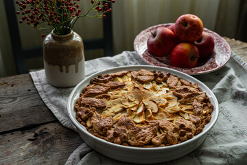 Homemade apple pie decorated with crust on wooden table in rustic kitchen.