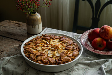 Homemade apple pie decorated with crust on wooden table in rustic kitchen.