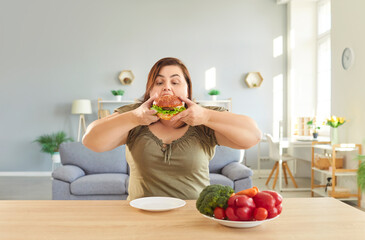 Obese hungry woman with excessive fat eating unhealthy fast food instead vegetables plate, tasty...