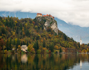 autumn view of lake bled with medieval castle on rocky hill and colorful forest in slovenia