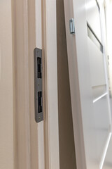 Installation of a black door handle with a lock for a white wooden door,