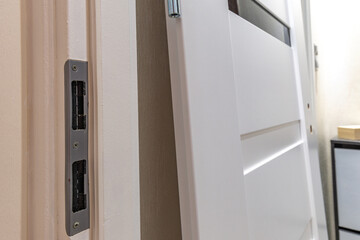 Installation of a black door handle with a lock for a white wooden door,