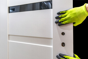 Installation of a black door handle with a lock for a white wooden door,