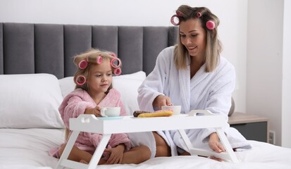 Mother and daughter having tea party on bed at home