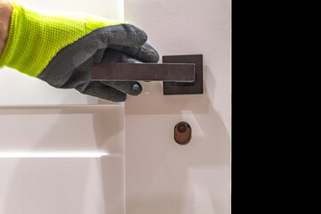 Installation of a black door handle with a lock for a white wooden door,