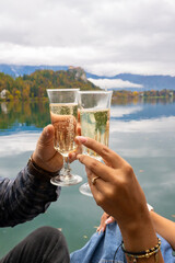 Young couple celebrating engagement with champagne by lake Bled in autumn scenic Slovenia