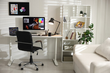 Stylish workplace with computer, laptop, cup, stationery and mat on desk indoors