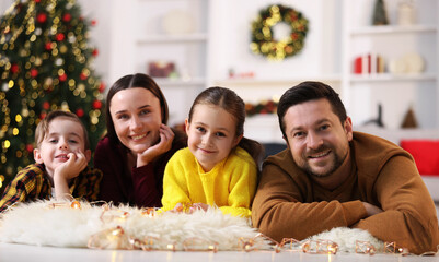Happy family on floor in room decorated for Christmas
