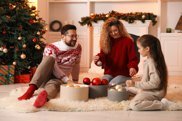 Happy family with ornaments near Christmas tree at home