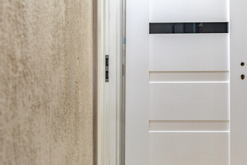 Installation of a black door handle with a lock for a white wooden door,