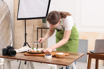Woman creating composition with croissants at table in studio. Professional food photography