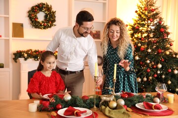 Happy family setting table in room decorated for Christmas