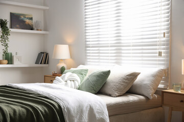 Stylish bedroom with large bed, pillows, houseplant and lamp. Interior design